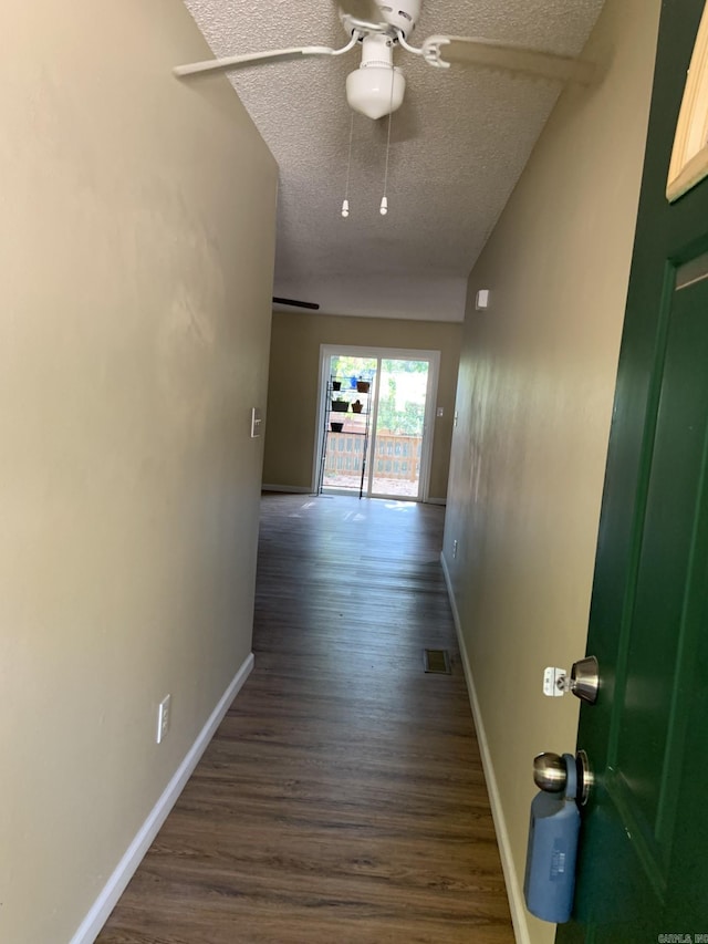 hallway featuring lofted ceiling, dark wood-type flooring, and a textured ceiling