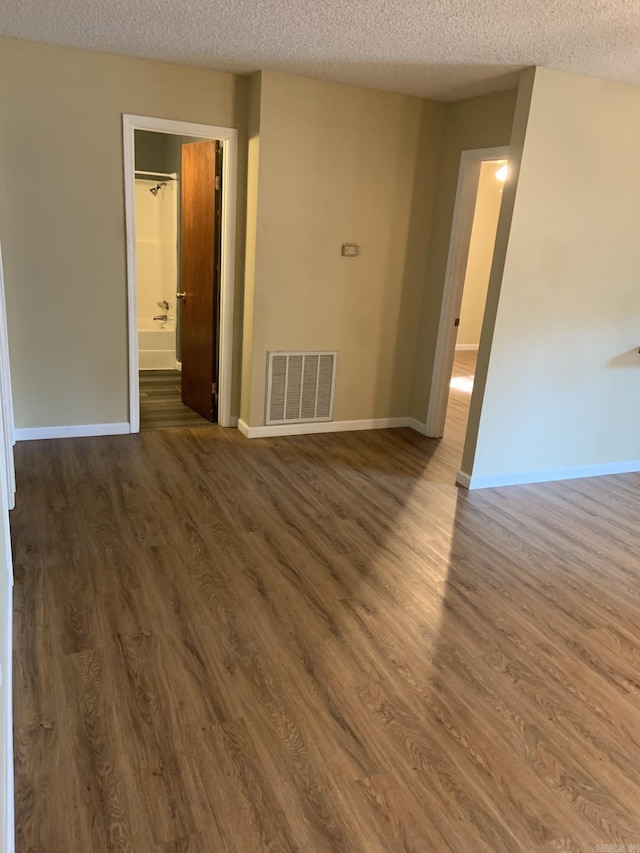 empty room with a textured ceiling and dark hardwood / wood-style floors