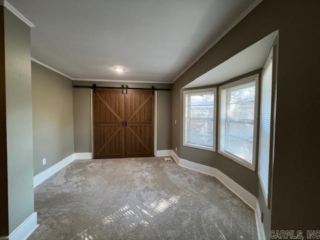 919 E Hamilton Ave, Wynne, AR 72396 - carpeted spare room featuring baseboards, ornamental molding, and a barn door