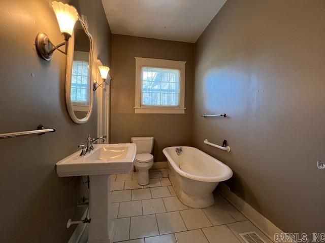 919 E Hamilton Ave, Wynne, AR 72396 - bathroom with a freestanding bath, tile patterned flooring, toilet, baseboards, and visible vents