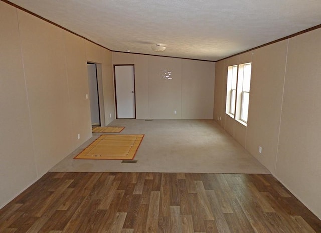 unfurnished room with crown molding, hardwood / wood-style floors, a textured ceiling, and vaulted ceiling