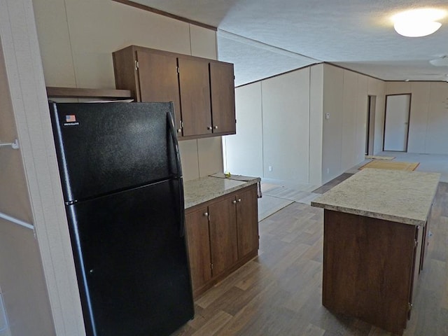 kitchen featuring light hardwood / wood-style flooring, a textured ceiling, and black fridge