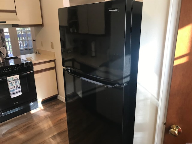 kitchen with black appliances, custom range hood, and wood-type flooring