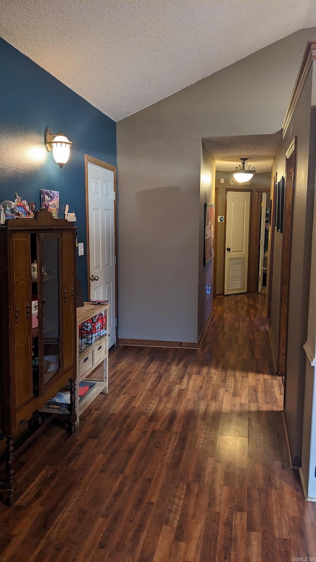 corridor featuring lofted ceiling, a textured ceiling, and dark hardwood / wood-style flooring