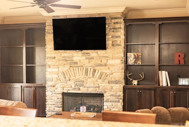 living room with crown molding, a stone fireplace, and ceiling fan