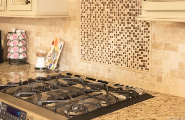 interior details with light stone countertops, stainless steel gas cooktop, and backsplash