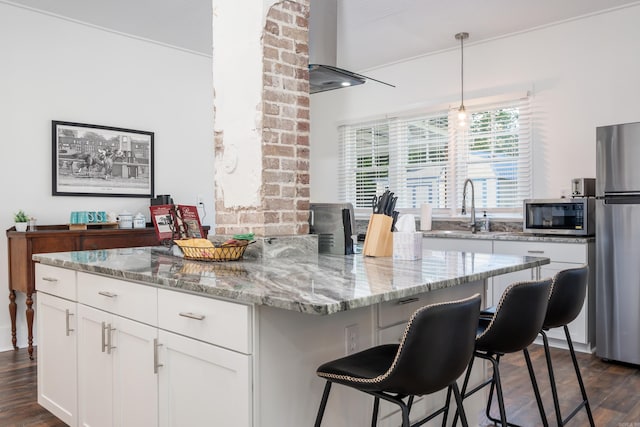 kitchen with a center island, stainless steel appliances, white cabinets, a breakfast bar, and dark hardwood / wood-style floors