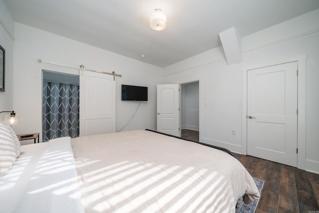 bedroom featuring a barn door and dark hardwood / wood-style floors