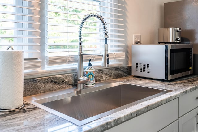 kitchen featuring white cabinetry and sink