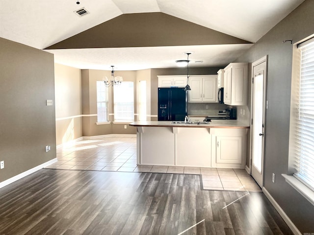 kitchen with hanging light fixtures, kitchen peninsula, plenty of natural light, and black appliances