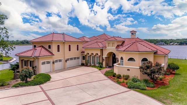 mediterranean / spanish-style house featuring a garage, a front lawn, and a water view