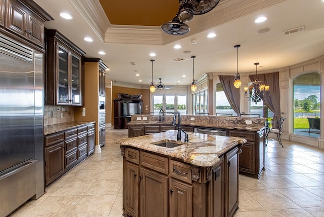 kitchen featuring decorative backsplash, hanging light fixtures, an island with sink, ornamental molding, and stainless steel appliances