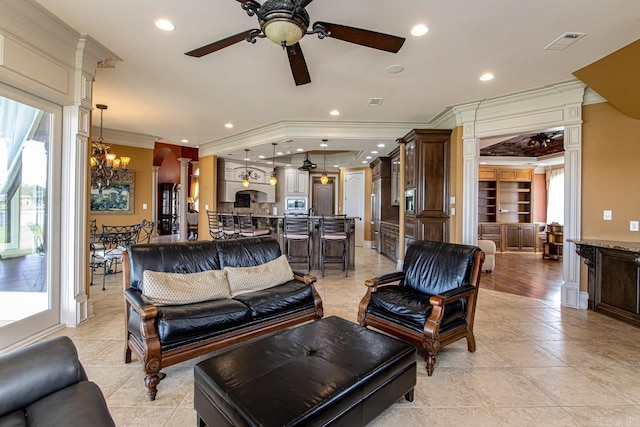 living room with ornate columns, ornamental molding, light tile patterned flooring, built in features, and ceiling fan with notable chandelier