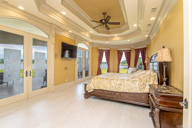 bedroom featuring a raised ceiling, access to exterior, hardwood / wood-style flooring, ornamental molding, and french doors