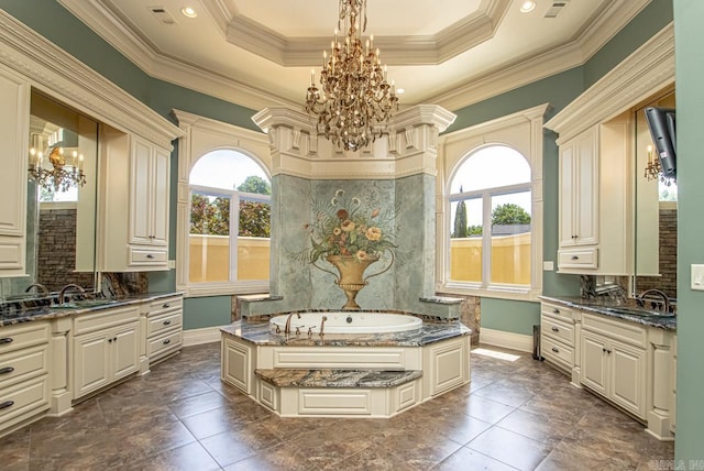 bathroom with a tub to relax in, a tray ceiling, ornamental molding, vanity, and a chandelier