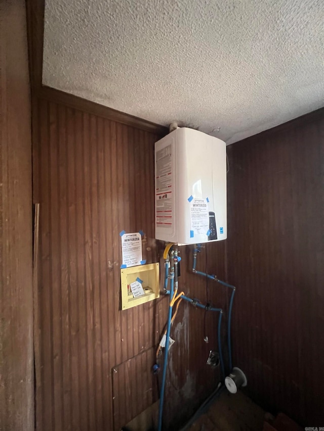 interior details with wooden walls, a textured ceiling, and tankless water heater