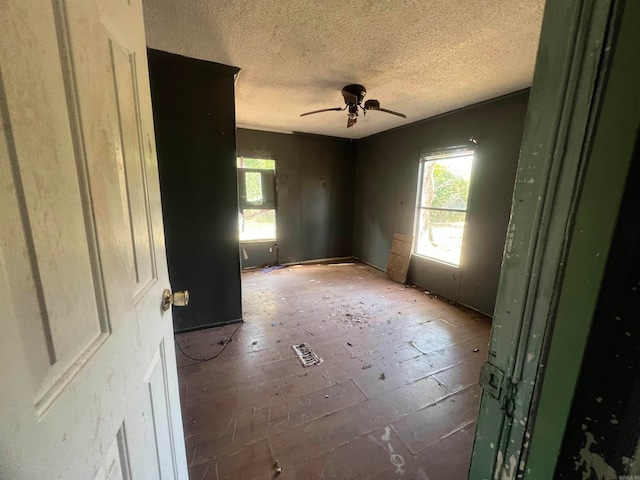 spare room featuring ceiling fan, a healthy amount of sunlight, and a textured ceiling