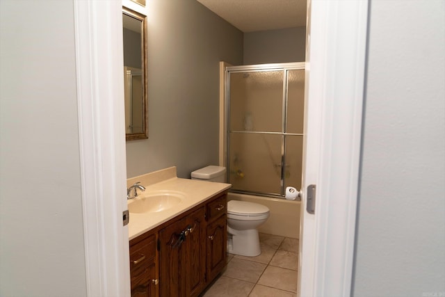 full bathroom with tile patterned floors, toilet, vanity, combined bath / shower with glass door, and a textured ceiling