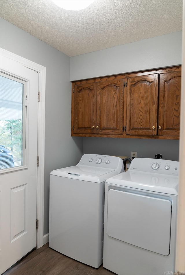 laundry room featuring cabinets, a textured ceiling, washer and clothes dryer, and dark hardwood / wood-style flooring