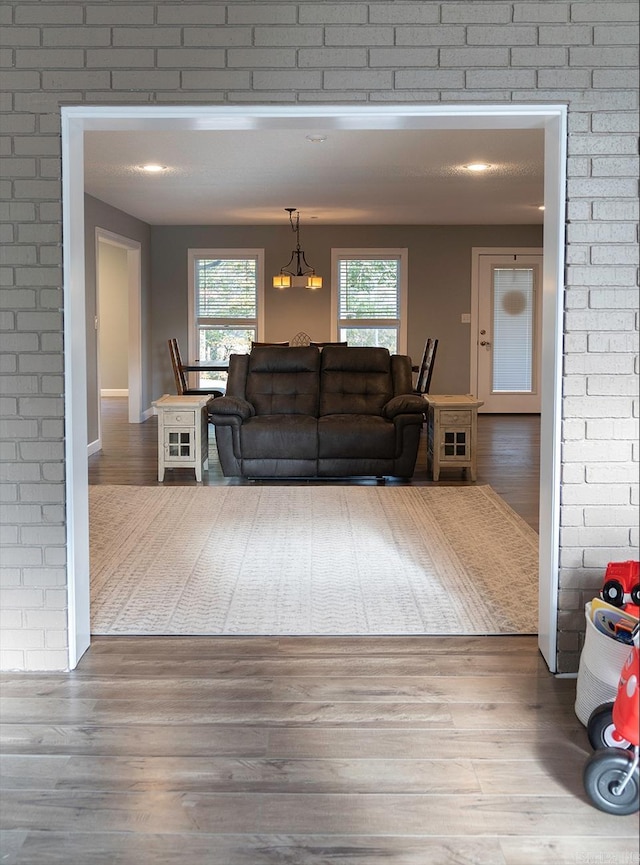 living room with brick wall, a chandelier, and hardwood / wood-style floors