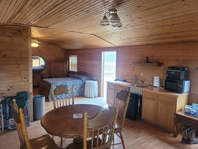 dining space featuring light hardwood / wood-style flooring, wood walls, sink, and wooden ceiling