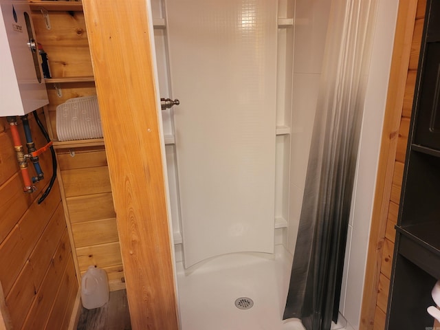 bathroom with wood walls and a shower with shower curtain