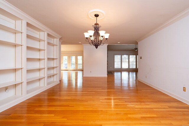 spare room featuring an inviting chandelier, light wood-type flooring, and a healthy amount of sunlight