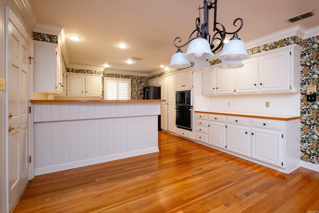 kitchen with ornamental molding, a notable chandelier, decorative light fixtures, light wood-type flooring, and white cabinetry