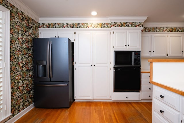 kitchen featuring black appliances, white cabinetry, and light wood-type flooring