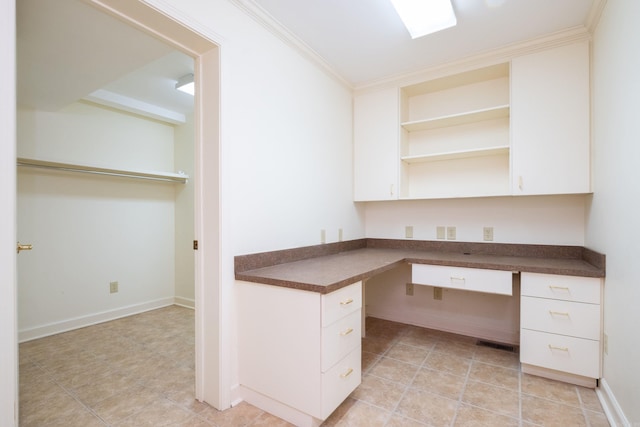 unfurnished office with crown molding, built in desk, and light tile patterned floors