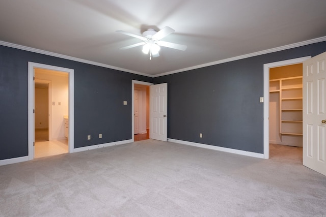 unfurnished bedroom featuring light carpet, a walk in closet, ensuite bath, and ceiling fan