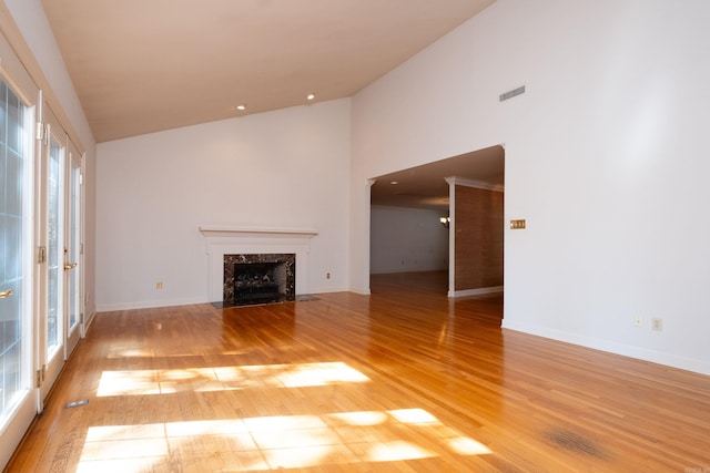 unfurnished living room with high vaulted ceiling, a premium fireplace, a wealth of natural light, and hardwood / wood-style floors