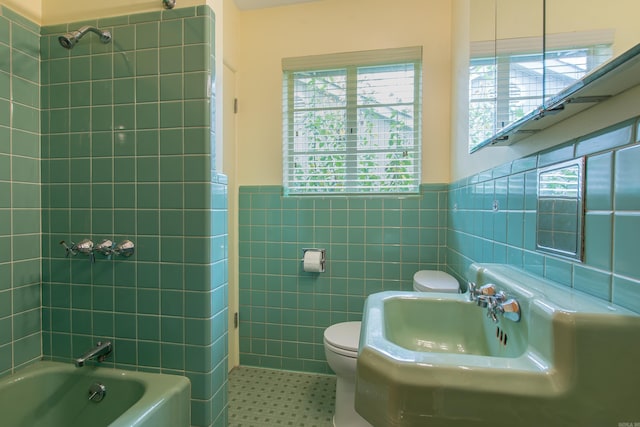 bathroom with tile walls, tiled shower / bath combo, and toilet