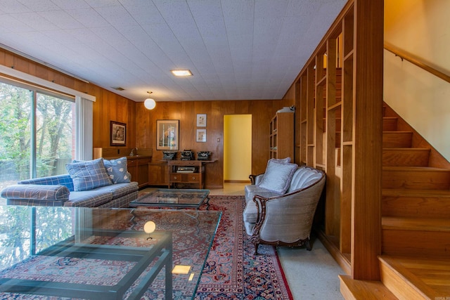 carpeted living room featuring wood walls