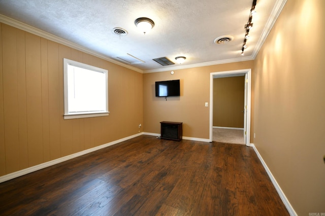 spare room with rail lighting, a textured ceiling, ornamental molding, dark wood-type flooring, and wooden walls