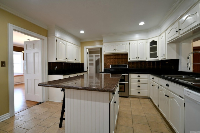 kitchen with dishwasher, a center island, decorative backsplash, and white cabinetry