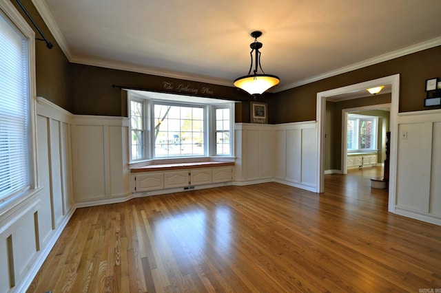 301 Reine St, Mena, AR 71953 - unfurnished dining area with light wood-style floors, a wainscoted wall, and a decorative wall