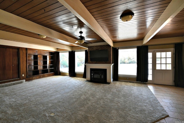 unfurnished living room featuring beamed ceiling, ceiling fan, a brick fireplace, and wooden ceiling