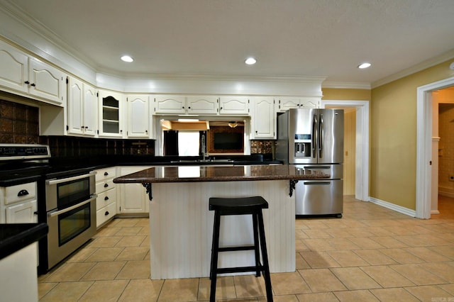301 Reine St, Mena, AR 71953 - kitchen featuring appliances with stainless steel finishes, decorative backsplash, a breakfast bar, and white cabinetry