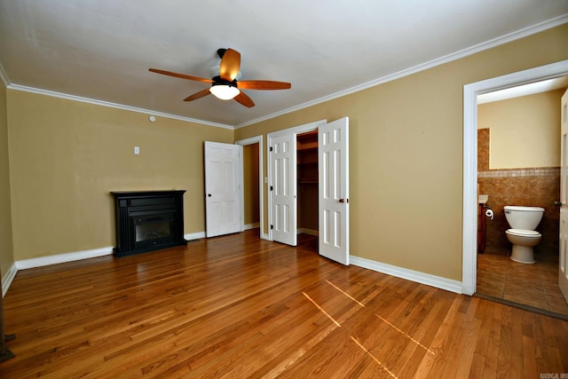 301 Reine St, Mena, AR 71953 - unfurnished living room with crown molding, ceiling fan, a glass covered fireplace, and wood finished floors
