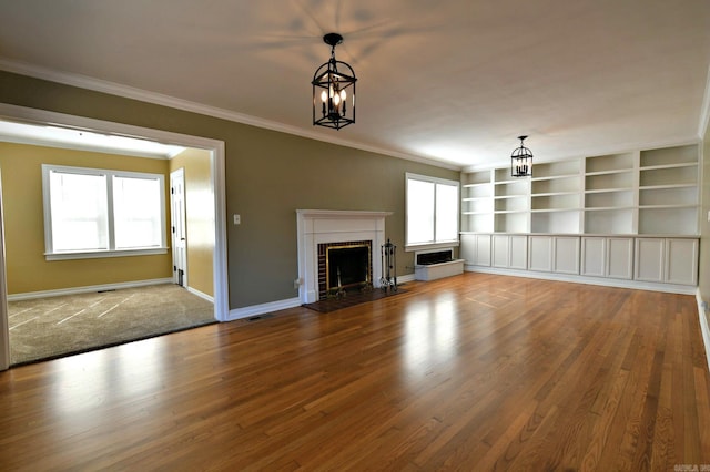 unfurnished living room with hardwood / wood-style flooring, a notable chandelier, and crown molding