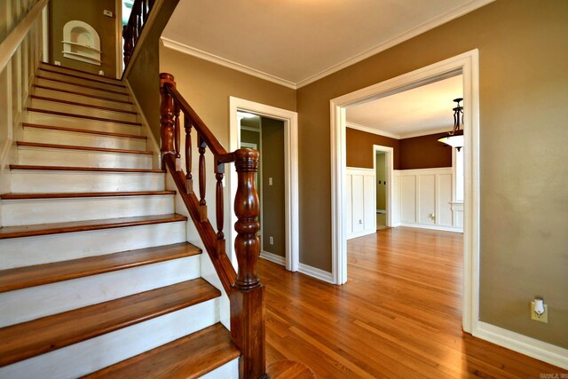 stairway with crown molding and hardwood / wood-style floors