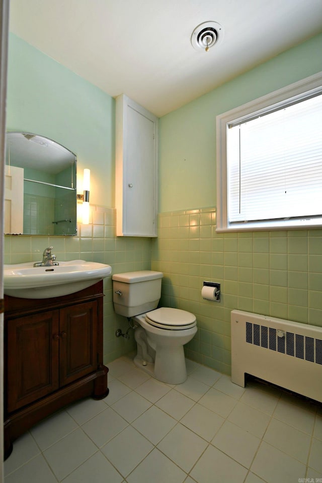 bathroom featuring tile patterned floors, toilet, vanity, tile walls, and radiator heating unit