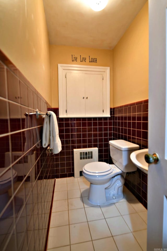 bathroom featuring toilet, radiator heating unit, tile patterned floors, and tile walls