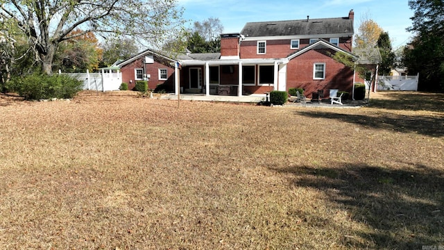 rear view of house with a lawn and a sunroom