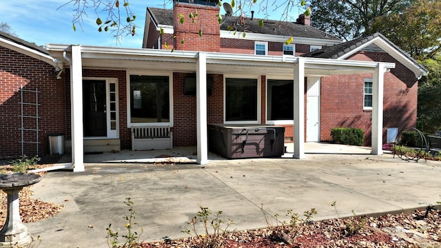 301 Reine St, Mena, AR 71953 - rear view of house featuring a hot tub, brick siding, a chimney, and a patio area
