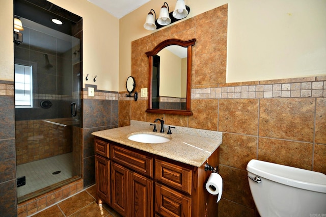 bathroom featuring a shower with door, toilet, tile walls, vanity, and tile patterned flooring