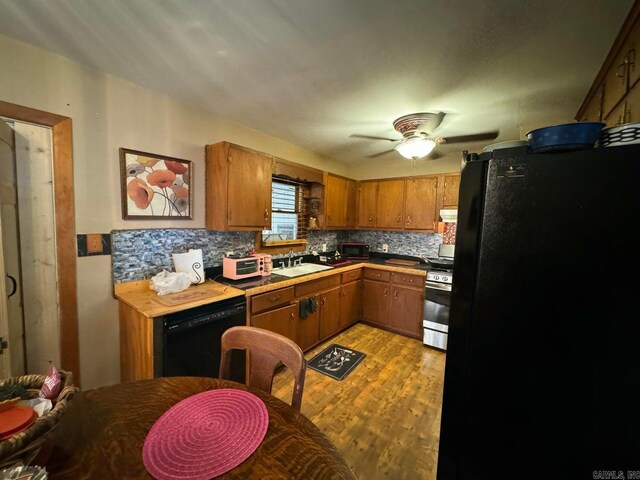 kitchen featuring black appliances, sink, backsplash, light hardwood / wood-style floors, and ceiling fan