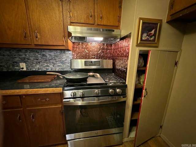 kitchen featuring tasteful backsplash, stainless steel range with gas cooktop, wood-type flooring, and ventilation hood