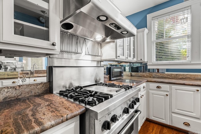 kitchen featuring white cabinetry, dark stone counters, stainless steel stove, extractor fan, and dark hardwood / wood-style floors